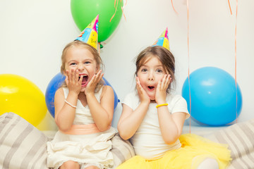 Two little girls amazed by a show at birthday party