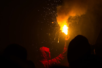Hooded person holding torch