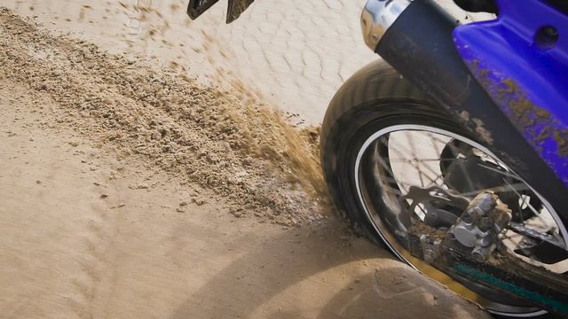Motorcyclist scatters sand rear wheel.