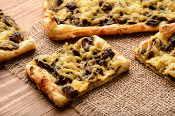 Puff pastries with mushrooms and cheese on wooden background.
