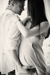 Expecting young woman leans to man's shoulder while he hugs her