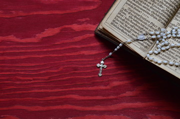 rosary with very old ancient book in old German lettering on red wooden table