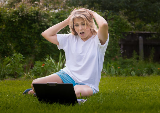 Красивая женщина на траве в саду с ноутбуком