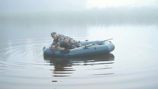 A fisherman casts anchor for inflatable boats. Early morning fog on the lake