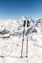 Zelfklevend Fotobehang skiing in mountains, close up of two ski poles sticks © EdNurg