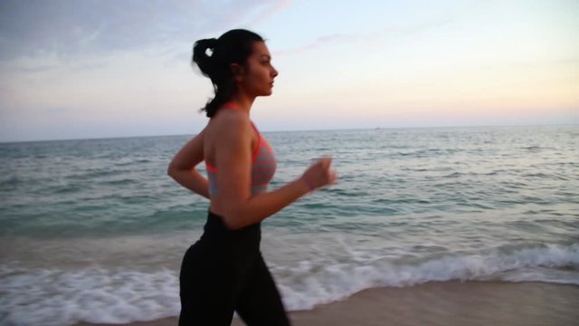 Sport leisure girl running on the beach of Mediterranean Sea at sunset