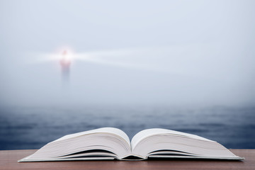 Wisdom concept - open book over sea and lighthouse background