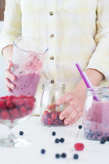 Close up of a female hands making a smoothie with fruits and ber