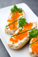Red caviar on bread on white plate.