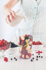 Close up of a young woman prepare to blending fruits with milk