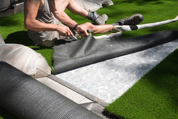 professional gardener is cutting artificial turf to fit