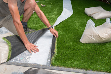 professional gardener is cutting artificial turf to fit