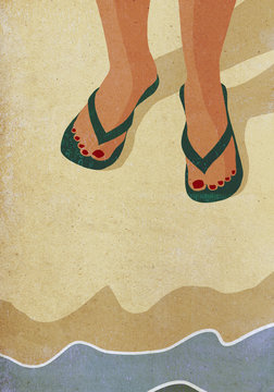 Low section of woman wearing slippers standing at sea shore