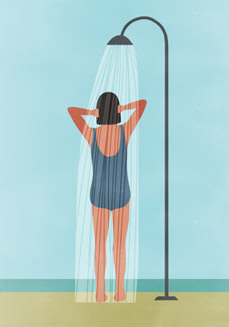 Rear view of woman having outdoor shower at beach
