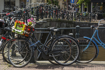 Fototapeta na wymiar Bike with flower basket on the street near the canal in Amsterdam in Europe
