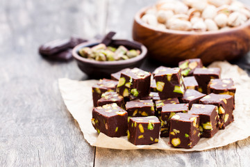 Dark  chocolate cubes with pistachios on wooden background