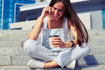  Woman in stylish overalls sitting on stairs with crossed legs a