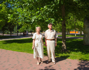 The happy old couple in the summer on a walk