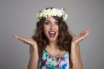 Amazed woman with floral tiara looking at camera over gray studio background © sharplaninac