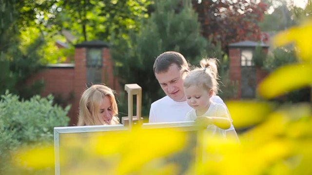 Young family painting on an easel in the garden.