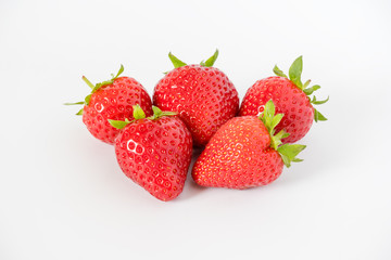 Cluster of ripe red whole fresh strawberries with green stalks and flower buds on a light grey background with