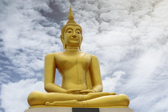 Gold image of Buddha with blue sky and cloud in background, light effect added , prachuapkhirikhan,thailand,filtered image