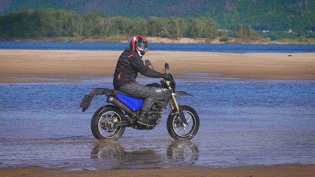 The feeling of freedom and Moto aesthetics. Motorcyclist riding on his bike on sandy beach.
