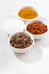 assortment of pepper, salt and spices in bowls, vertical
