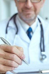 Male medicine doctor hand holding silver pen writing something on clipboard closeup. Ward round, patient visit check, medical calculation and statistics concept. Physician ready to