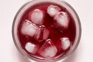 Acai juice in a glass with ice on pink background