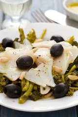 cod fish with olives and greens on white plate