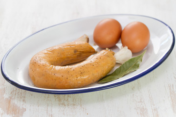 portuguese sausage alheira with eggs on white dish on white wooden background