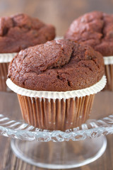 chocolate muffins on dish on brown wooden background