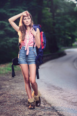 Backpacker girl standing by the road