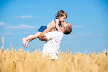 father and son having fun outdoor in wheat field