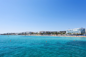 Photo of sea and fig tree bay beach in protaras, cyprus island with swimming people and hotels.
