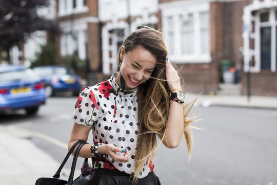 UK, London, portrait of smiling young woman with blowing hair