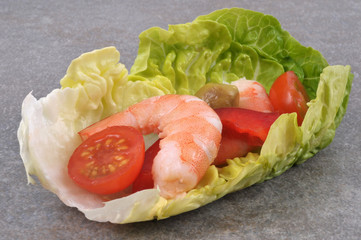 Amuse-bouche composé d'une feuille de salade, de crevette, de tomate cerise, de poivron et d'olive
