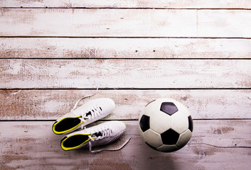 Soccer ball, cleats on white wooden floor, studio shot