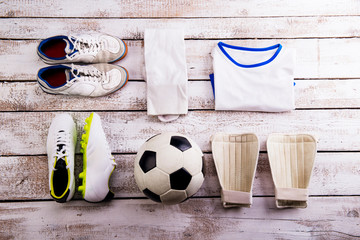 Soccer ball,cleats and various football stuff, wooden background