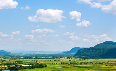 Fototapeta na wymiar Country landscape in mountain valley with farmland on blue sky
