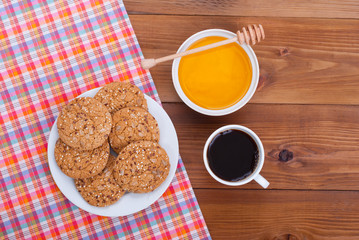Coffee cup biscuits and honey lies on a wooden background.