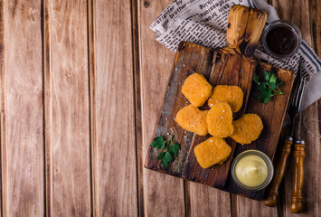 Chicken Nuggets on wooden cutting board with ketchup and sauce, on wooden background. Selective focus. Top view