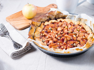 Home made apple galette with cherry jam and pine nuts on beige table cloth