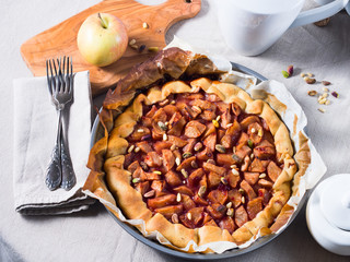 Home made apple galette with cherry jam and pine nuts on beige table cloth