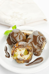 Profiteroles dessert with cream and chocolate glaze on a plate