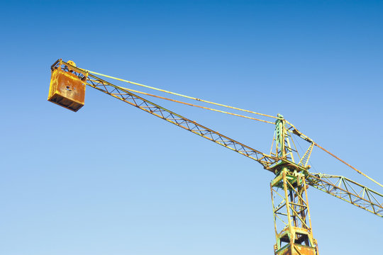 Old rusty tower crane in a blue background