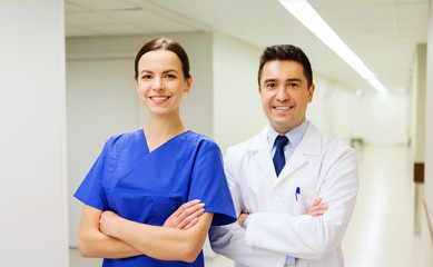 smiling doctor in white coat and nurse at hospital