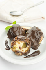 Profiteroles dessert with cream and chocolate glaze on a plate