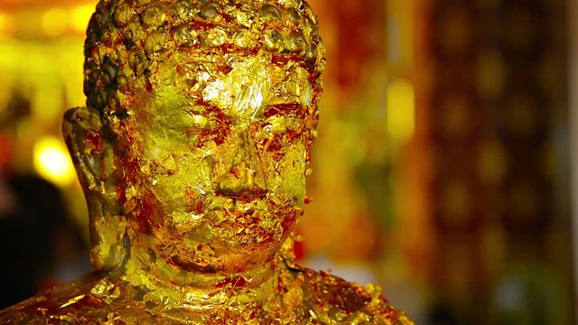 FullHD video - Typical Buddha sculpture covered in many layers of gold leaf, a traditional offering to placate spirits and make requests, at a shrine in Ayutthaya, Thailand.